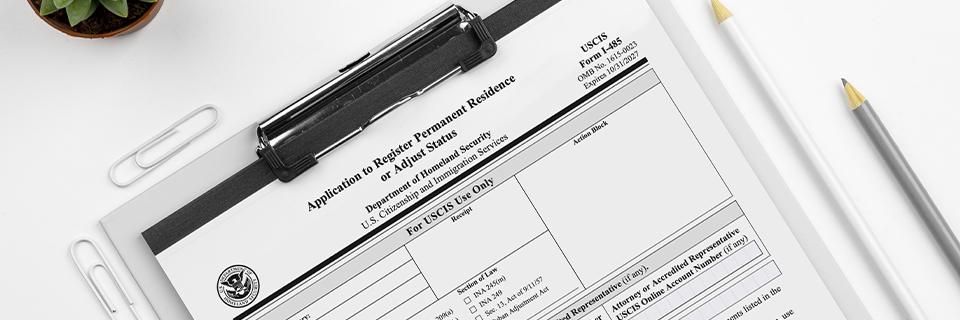 USCIS Form I-485 application on a clipboard, illustrating the EB5 adjustment of status process for permanent U.S. residency.