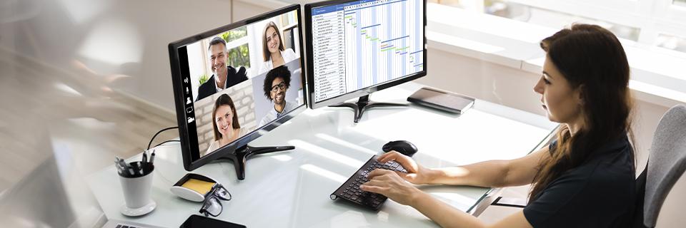 EB5 Green Card holder working remotely on dual-screen setup, representing employment flexibility for investors with work authorization.