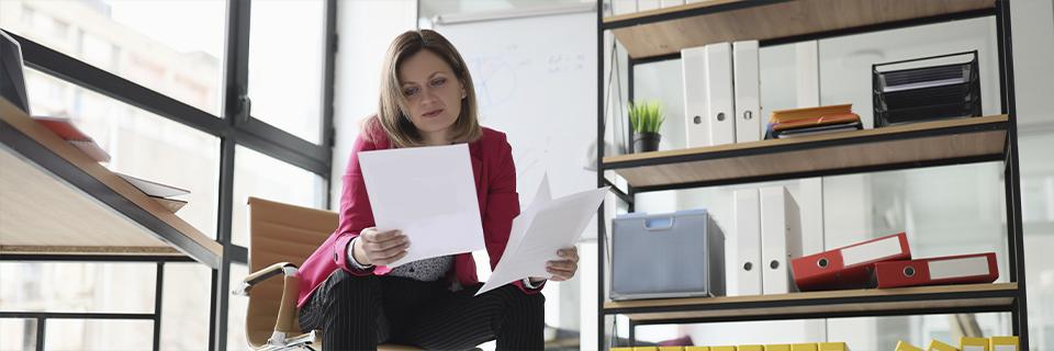 A businesswoman reviewing documents in a modern office surrounded by files—depicting an EB5 investor analyzing the reasons behind a visa denial.