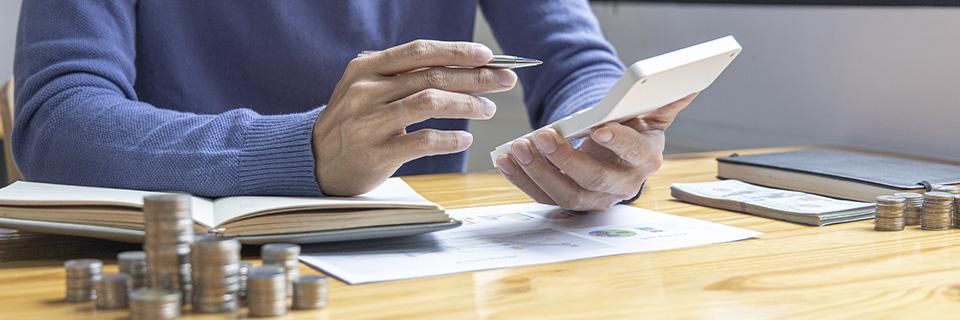 A person calculating EB5 investment installments using a calculator and financial documents, symbolizing step-by-step planning for funding a U.S. Green Card through partial payments.