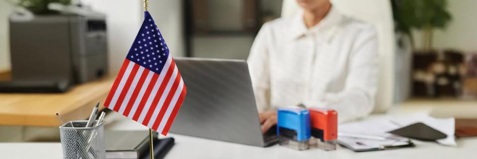 Close-up of a small American flag on a desk in a modern office, symbolizing the EB5 process and legal steps involved in obtaining visas.