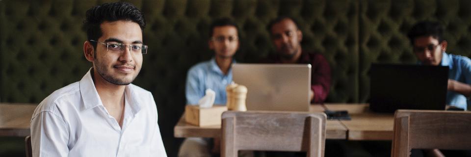 Indian EB5 investor seated confidently in a cafe setting, symbolizing independent immigration planning outside of employer sponsorship.