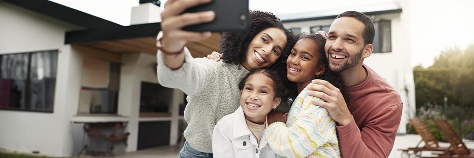 A smiling family taking a selfie outside a newly built single-family home, symbolizing the lifestyle appeal and demand driving EB5 housing project success.