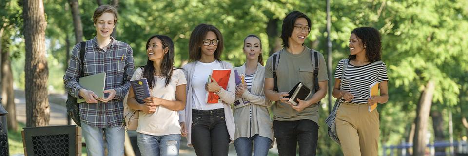 Group of diverse international students walking on a U.S. college campus, symbolizing F1 visa holders exploring future opportunities like the EB5 Green Card program.
