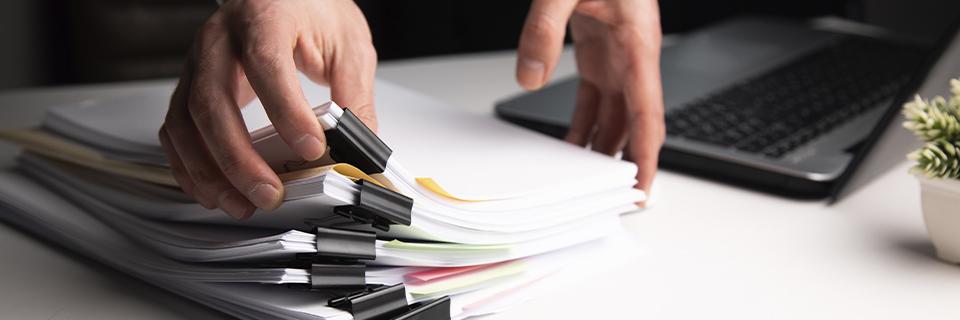 Close-up of hands organizing EB5 documentation, highlighting the heavy paperwork burden of direct investments.