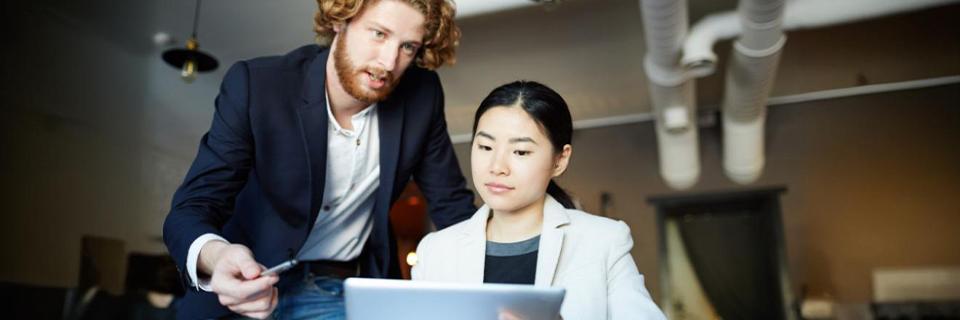 Professional man and woman collaborating in an office setting, representing employment flexibility through EAD and EB5 Green Card pathways.