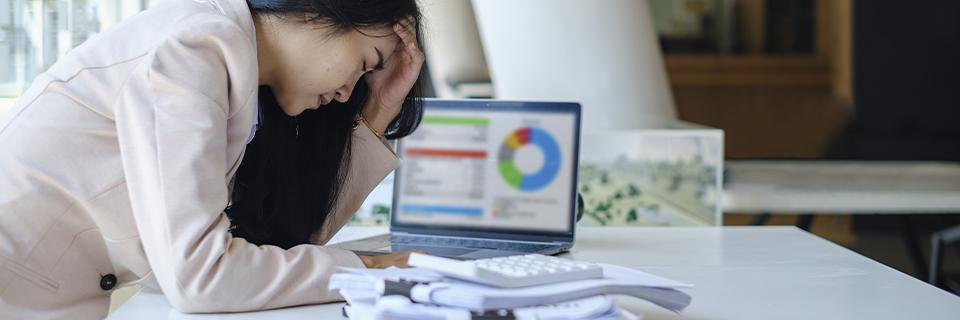 Concerned businesswoman reviewing financial charts and documents, illustrating the operational stress of managing a direct EB5 business.