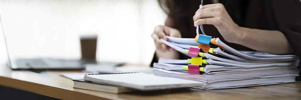 An individual preparing detailed paperwork with color-coded tabs, highlighting the documentation required for EB5 source of funds and installment tracking.