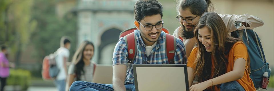 A group of Indian students sitting outdoors and studying together on a laptop, symbolizing EB5 families planning U.S. education opportunities while navigating age-out risks.