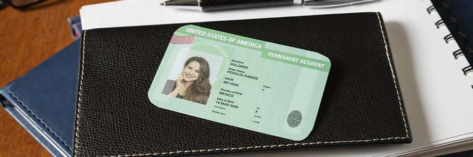 A close-up of a U.S. permanent resident card placed on a black leather wallet, representing lawful permanent residency through a Green Card.