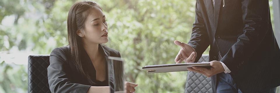 An EB5 investor reviewing documents with a consultant holding a tablet, representing guidance on meeting the EB5 at-risk investment rule.