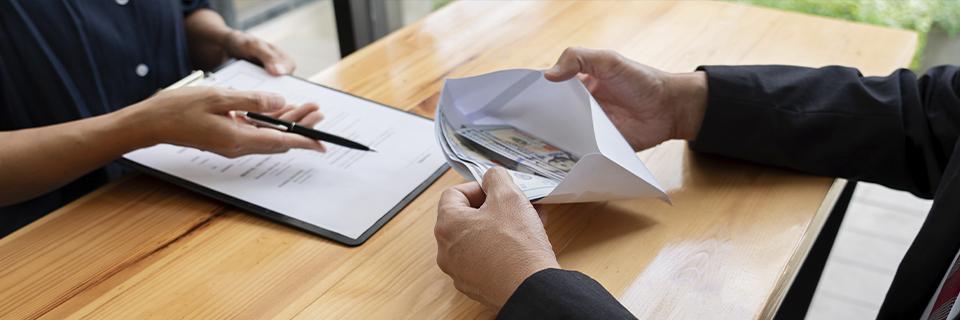 An investor reviewing EB5 loan documents while money is exchanged in an envelope, representing repayment arrangements and financial safeguards.