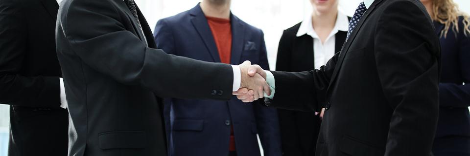 Two professionals in business suits shaking hands, representing EB5 investors partnering with experienced regional centers to secure Green Cards for their families.