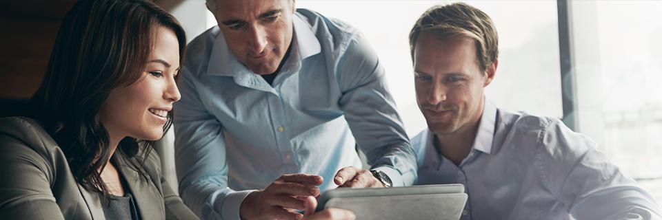 A group of EB5 professionals discussing project details on a tablet, symbolizing teamwork in ensuring investments meet at-risk rule compliance.