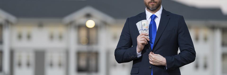 A businessman placing US dollar bills into his jacket pocket, symbolizing EB5 investment funds and financial commitment.