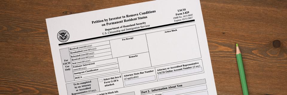 Form I-829 Petition by Investor to Remove Conditions on Permanent Resident Status with a pencil on a wooden desk, illustrating the EB5 process of removing Green Card conditions.