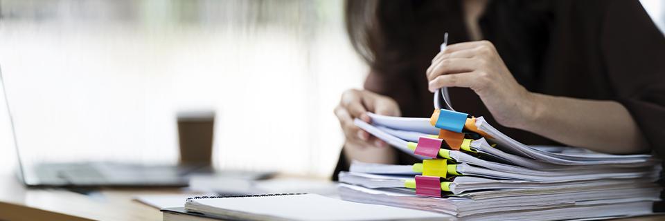 A professional reviewing thick stacks of case files with colorful tabs, representing EB5 petition paperwork and documentation for legal review.