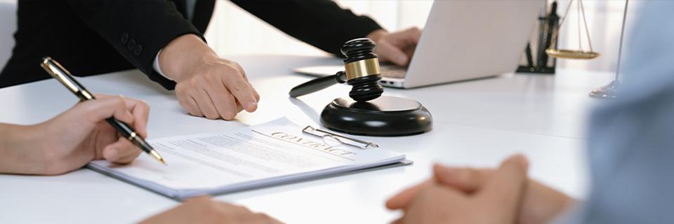 Lawyers discussing documents in an office with a gavel and scale of justice, illustrating EB5 investors considering mandamus action to move their cases forward.