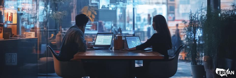 Two tech professionals working late in a modern glass office, illustrating career flexibility and stability gained through the EB5 program.