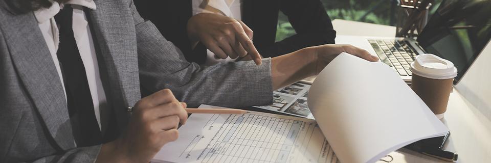 Two professionals pointing at paperwork in an office setting, highlighting professional guidance provided by EB5AN for EB5 investors in proving source and path of funds.