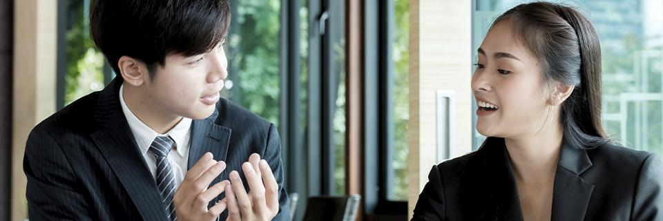 Two business professionals discussing documents in an office, symbolizing EB5 investors communicating across language barriers.