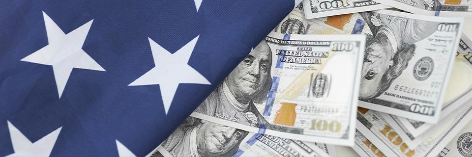 Close-up of the US flag over one hundred dollar bills, representing EB5 investment funds and American residency opportunities.