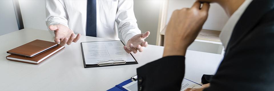 Close-up of a business meeting where one person explains documents to another, symbolizing translation and interpretation support in the EB5 immigration process.