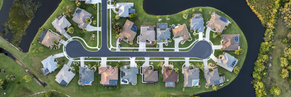 Top-down view of a completed residential cul-de-sac surrounded by water and greenery, representing stable housing demand in EB5 communities.