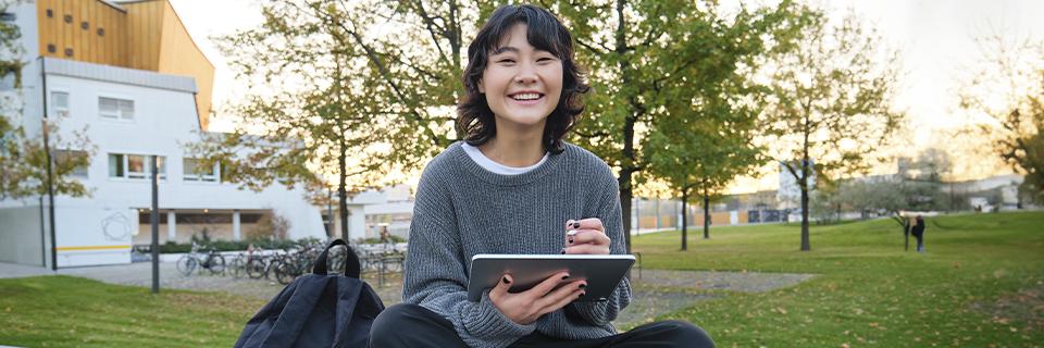 A university student sitting on campus with a tablet, symbolizing F1, OPT, and EB5 pathways for international students planning long-term careers in the United States.