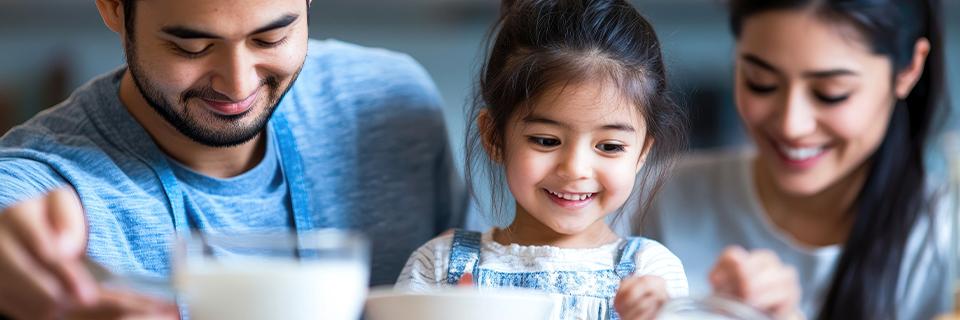 A family with parents and a young child sharing a meal at home, symbolizing EB5 investors including their spouse and children in a family-based EB5 immigration application.