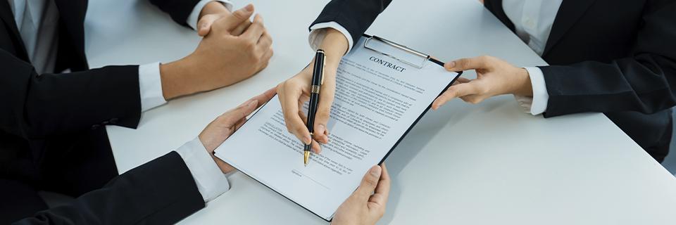 Business professionals reviewing and signing a contract, illustrating the EB5 redemption agreement process where investor interests are formally redeemed and capital repayment terms are finalized.