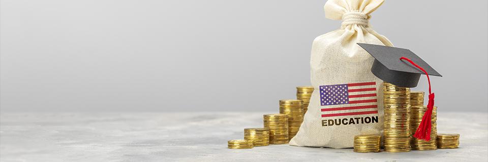 A graduation cap placed on stacked coins beside an education savings bag, symbolizing EB5 investors using U.S. Green Card benefits to access affordable education for their children.