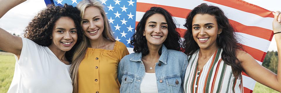 A group of young women standing in front of a U.S. flag, representing EB5 families benefiting from long-term residency, global mobility, and future U.S. citizenship.