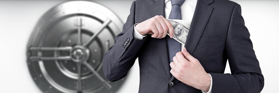A business professional placing cash into an inner jacket pocket in front of a vault door, symbolizing protecting EB5 investment capital and financial security.