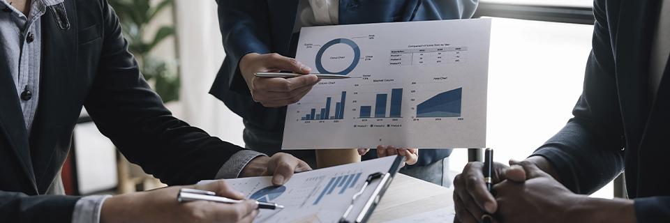 A group of professionals reviewing printed financial charts and graphs during a meeting, symbolizing EB5 investors and advisors analyzing project financial structure and capital stack before selecting an EB5 investment project.